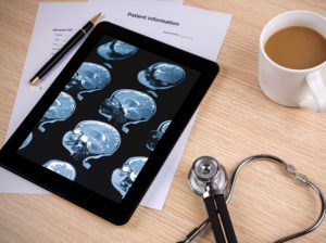 A tablet with a stethoscope and mri images on it.