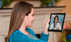 A woman is holding up a tablet with a woman on it.