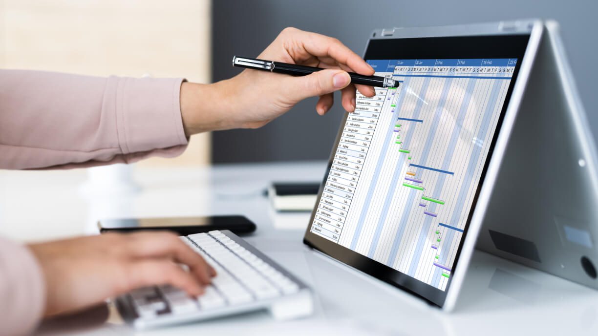 A woman is using management software on a laptop to view a project plan.