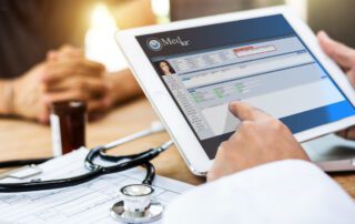 A person is using a tablet with a stethoscope, utilizing management software.