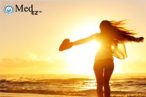 A woman is standing on the beach with her arms outstretched, demonstrating a sense of freedom and serenity.