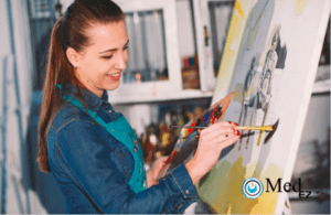 A woman is painting on an easel in an art studio.
